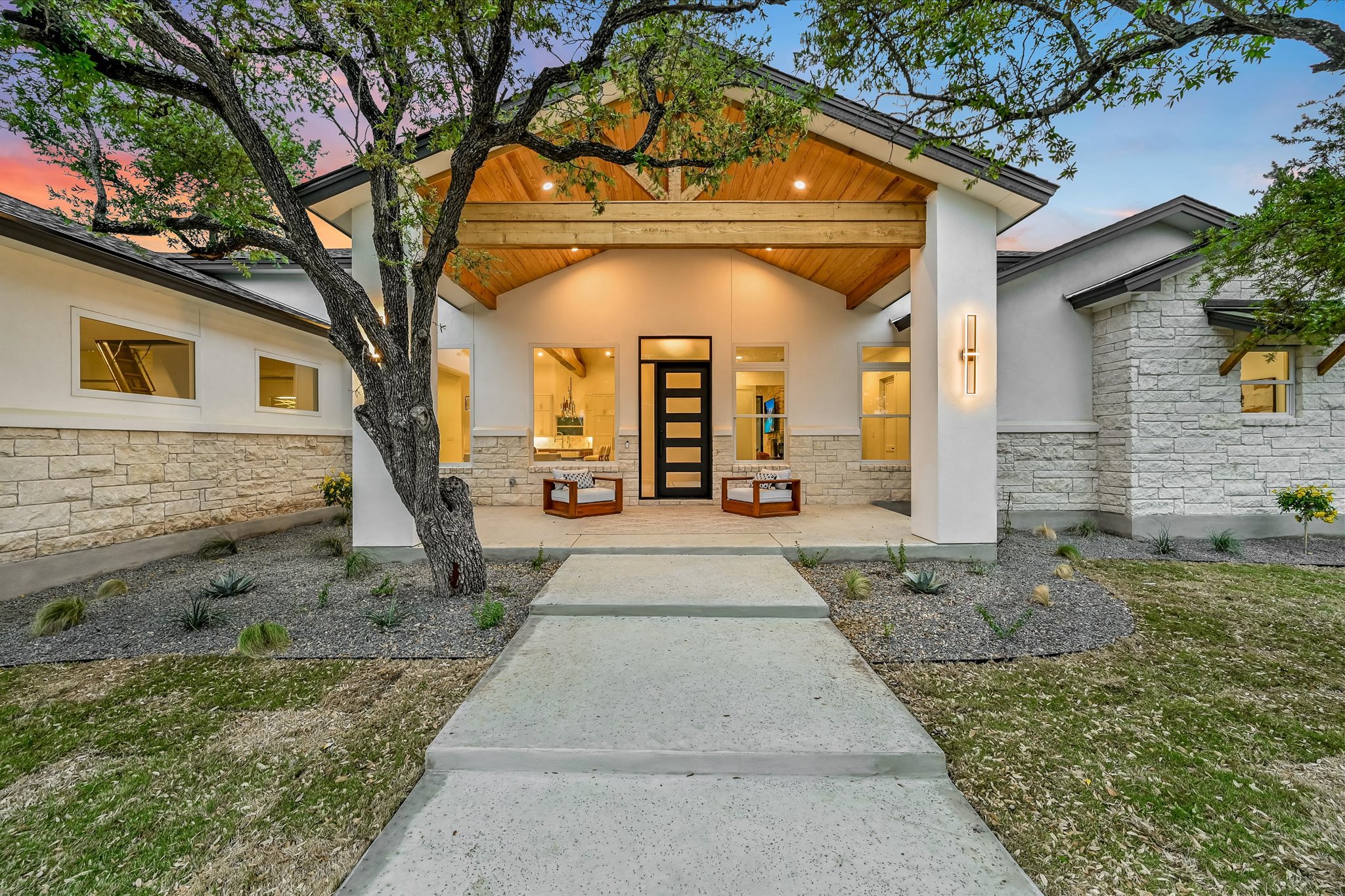 Exterior entry at dusk with stucco siding, stone siding, and a porch