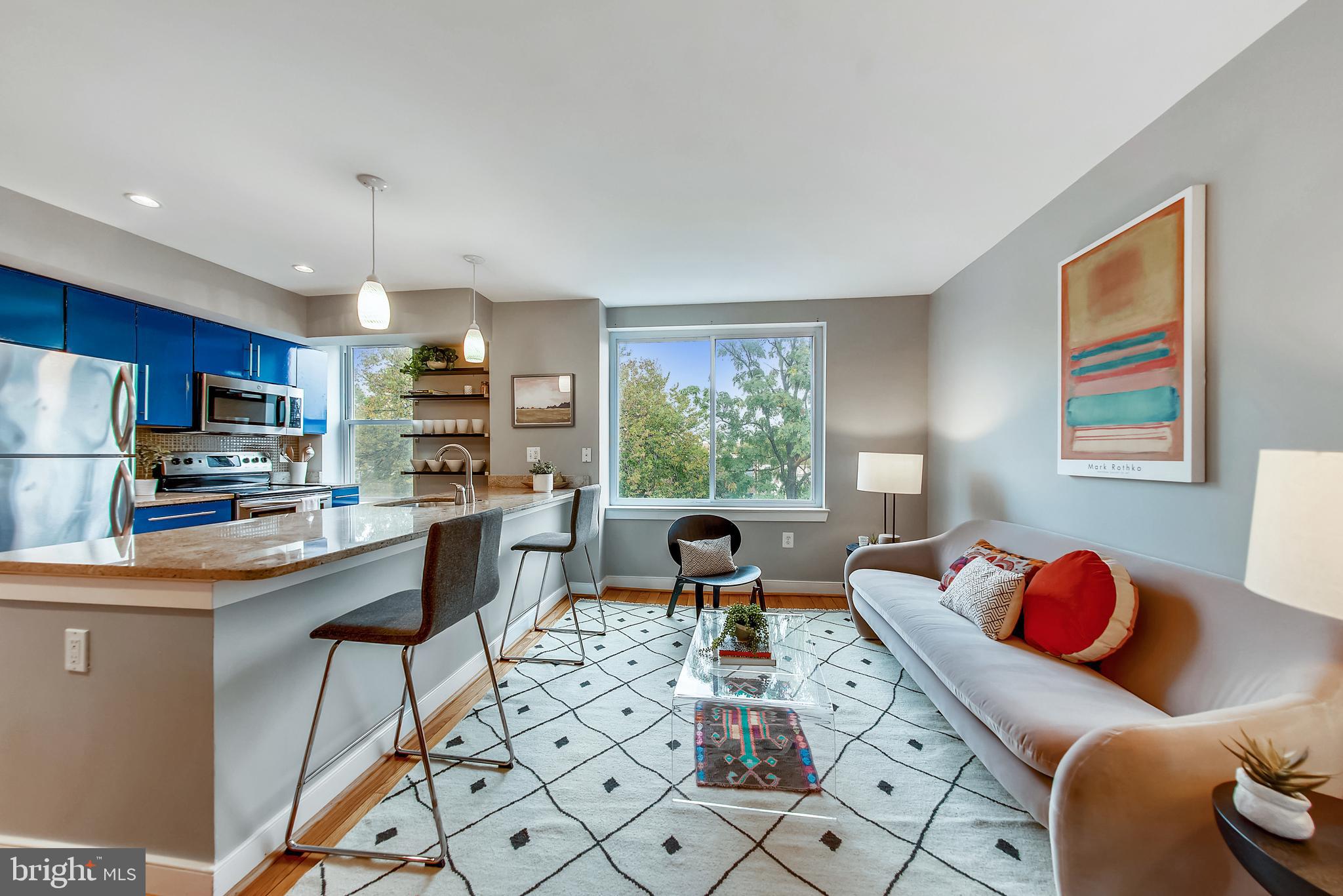 a living room with stainless steel appliances kitchen island granite countertop furniture and a large window
