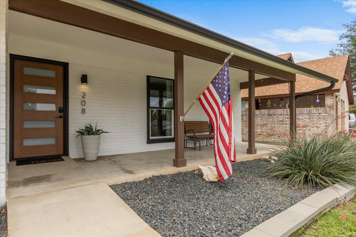 208 Skyloop Drive Austin, TX 78745 - Photo 4 of 34 Welcoming covered front porch with contemporary wood front door, clean landscaping, and plenty of space to relax.