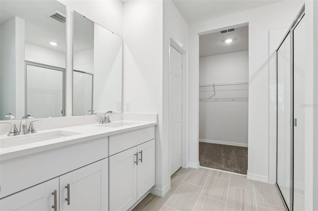 28009 Poppy Court Leesburg, FL 34748 - Photo 20 of 35 a spacious bathroom with a double vanity sink a mirror and shower