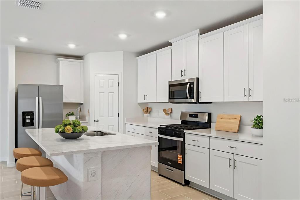 28009 Poppy Court Leesburg, FL 34748 - Photo 2 of 35 a kitchen with white cabinets and appliances