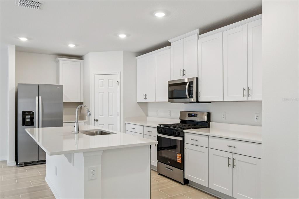 28009 Poppy Court Leesburg, FL 34748 - Photo 10 of 35 a kitchen with kitchen island granite countertop stainless steel appliances and white cabinets