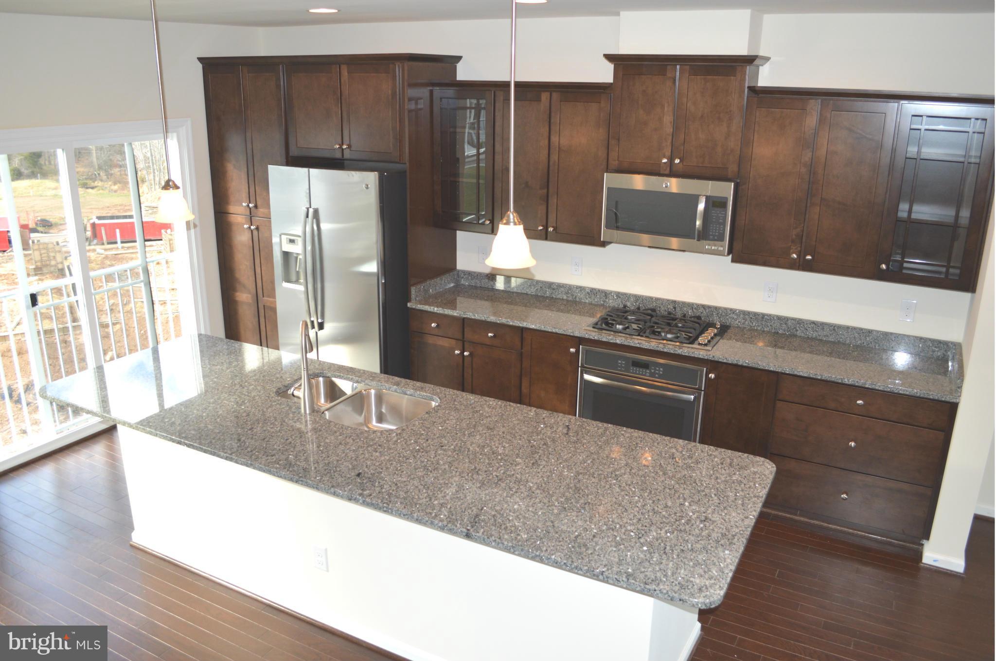 a kitchen with stainless steel appliances granite countertop wooden cabinets a refrigerator and a sink