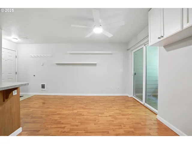 a view of an empty room with window and wooden floor