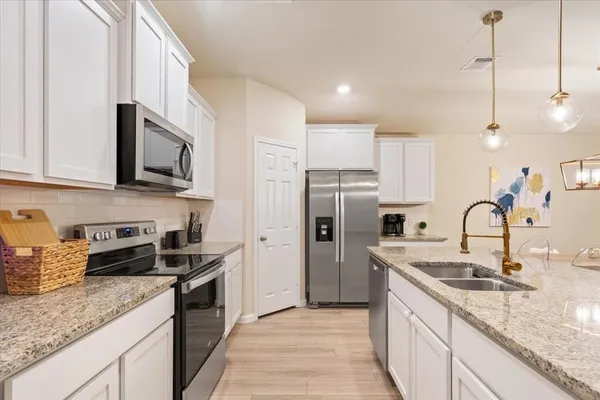 a kitchen with stainless steel appliances granite countertop a sink a stove a refrigerator and cabinets