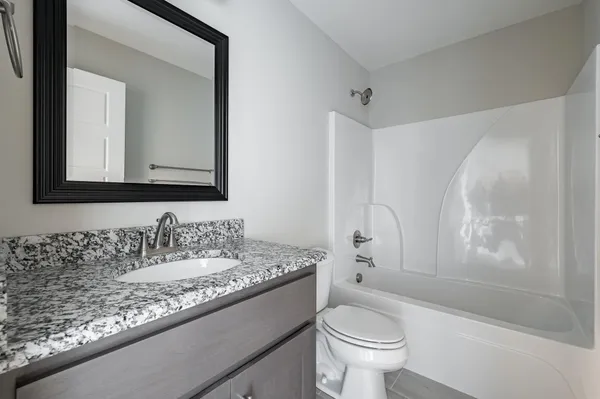 a bathroom with a granite countertop sink a toilet and a mirror