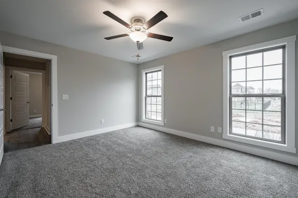 an empty room with windows and ceiling fan