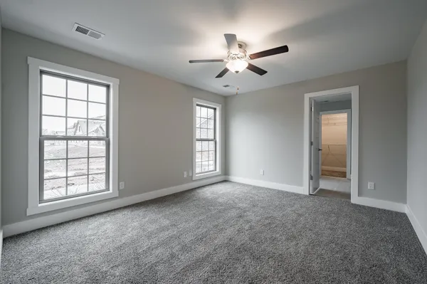 an empty room with windows and fan chandelier fan