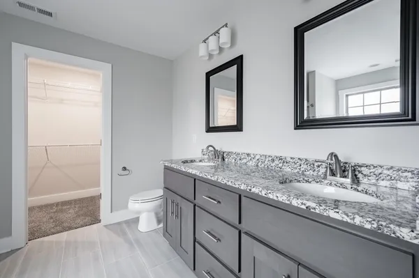 a bathroom with double vanity sink a mirror and a toilet
