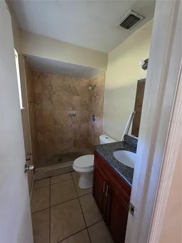 a bathroom with a granite countertop sink a toilet a mirror and shower