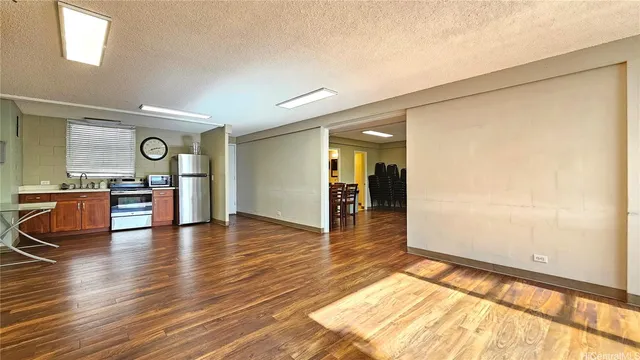 a view of an empty room and kitchen with furniture wooden floor and window