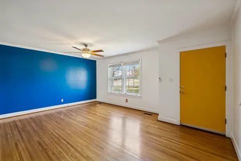 a view of an empty room with wooden floor and a window