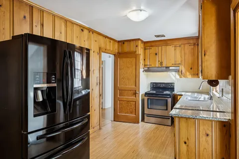 a kitchen with granite countertop a refrigerator stove and sink