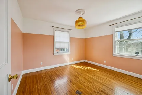 a view of empty room with window and wooden floor