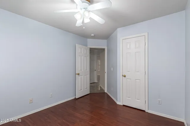 an empty room with wooden floor closet and fan