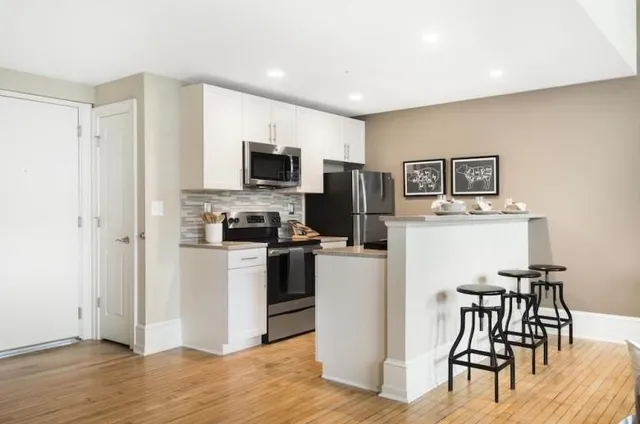 a kitchen with a refrigerator a stove top oven a dining table and chairs