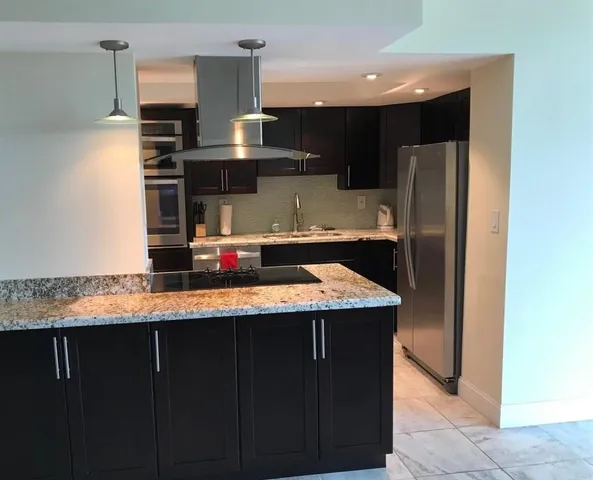 a kitchen with stainless steel appliances granite countertop a sink and a refrigerator