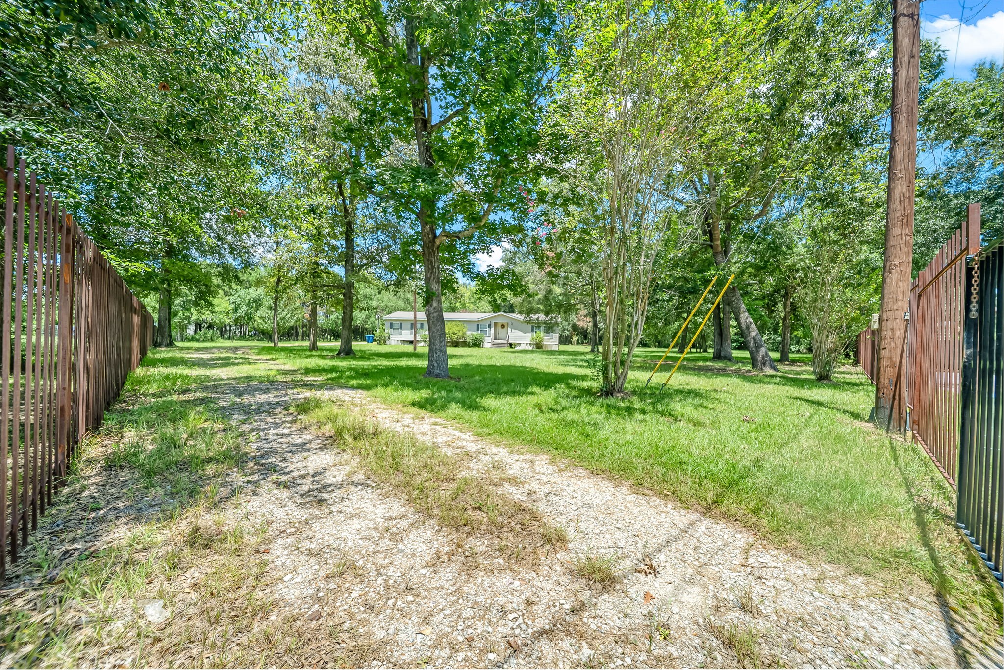 25979 Shade Tree Lane Splendora, TX 77372 - Photo 4 of 22 A metal fence and gated entrance welcome you onto the property, offering enhanced privacy, security, and a picturesque approach.