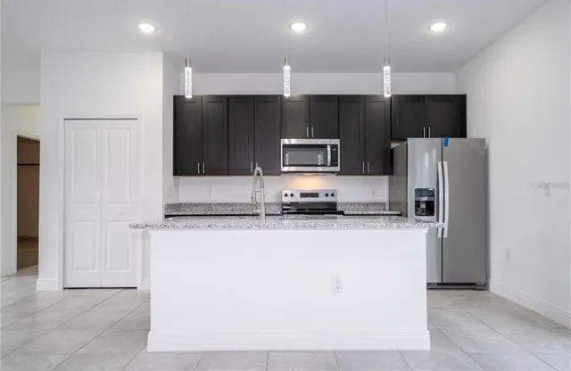 a kitchen with stainless steel appliances a refrigerator a stove a sink and a oven