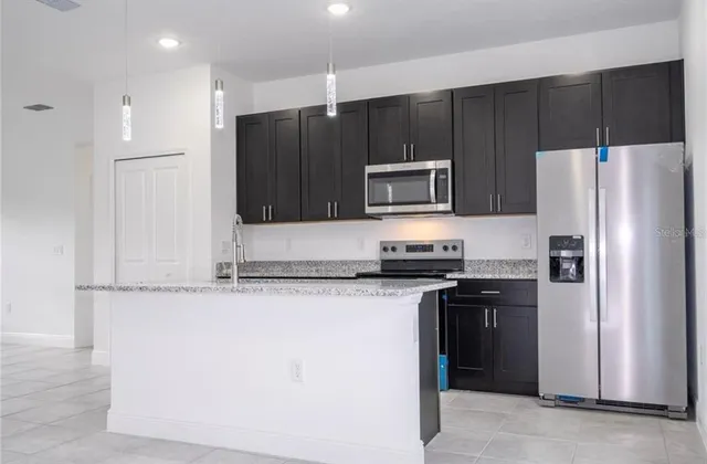a kitchen with granite countertop a refrigerator and a stove top oven