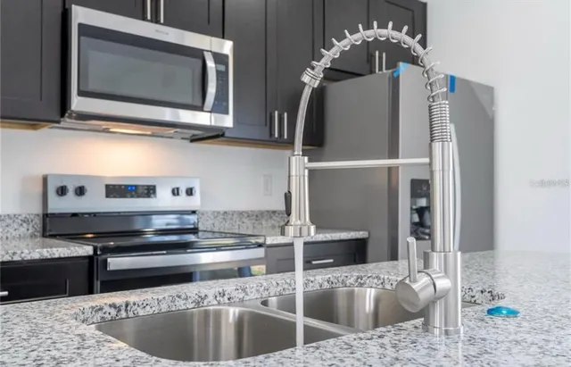 a kitchen with stainless steel appliances granite countertop a sink and a microwave