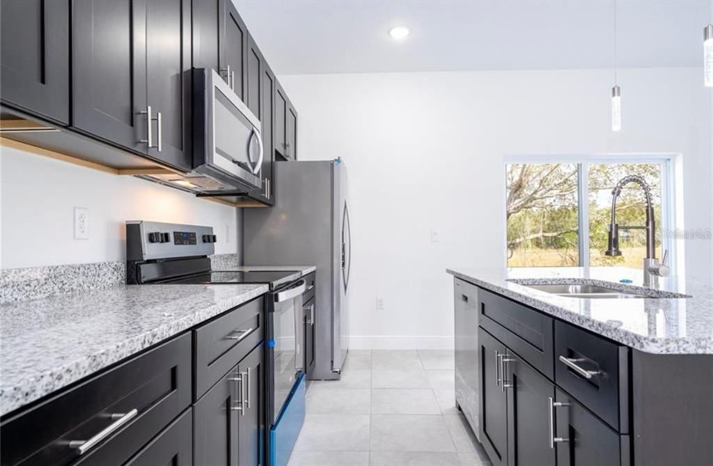 9809 North Swanee Terrace Citrus Springs, FL 34433 - Photo 18 of 46 a kitchen with stainless steel appliances granite countertop a sink a stove and a wooden cabinets