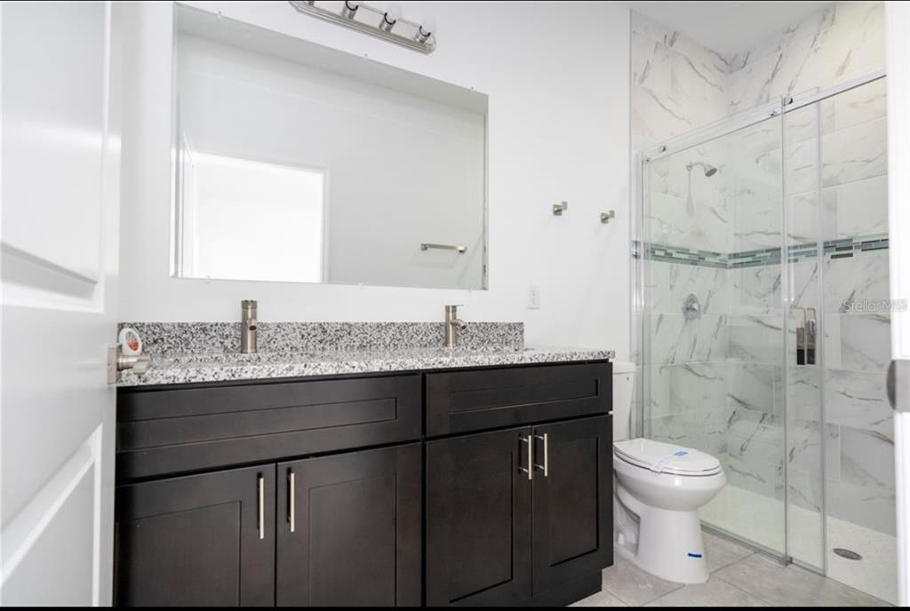 9809 North Swanee Terrace Citrus Springs, FL 34433 - Photo 29 of 46 a bathroom with a granite countertop sink toilet a mirror and shower