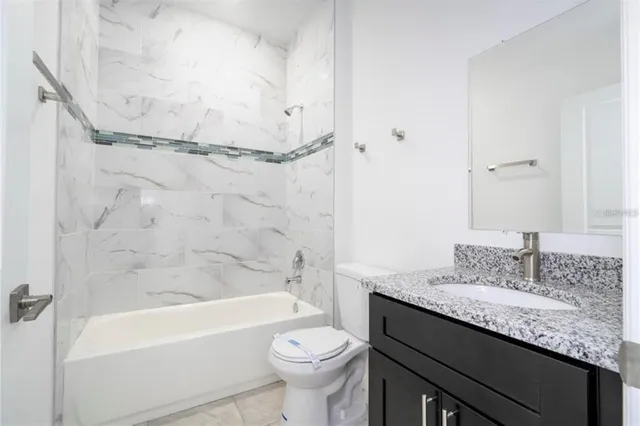 a bathroom with a granite countertop sink a mirror and shower
