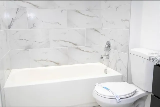 a bathroom with a granite countertop sink a toilet and a mirror