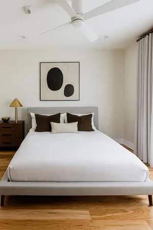 a bedroom with a bed and a lamp on dresser