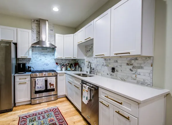 a kitchen with stainless steel appliances granite countertop a stove a sink and white cabinets