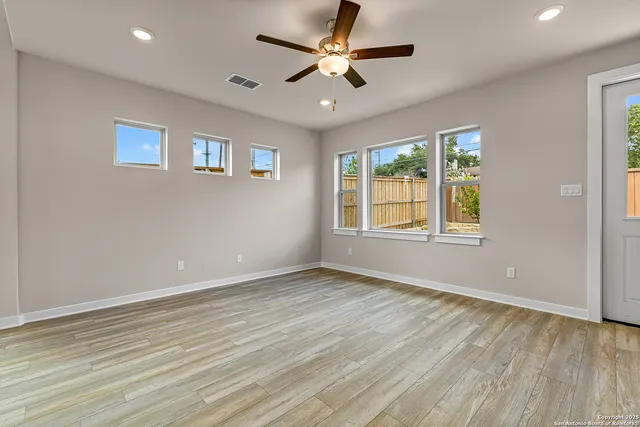 a view of an empty room with a window and wooden floor