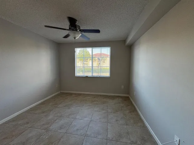 an empty room with windows and fan