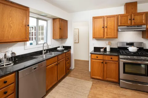a kitchen with stainless steel appliances granite countertop a sink stove and cabinets