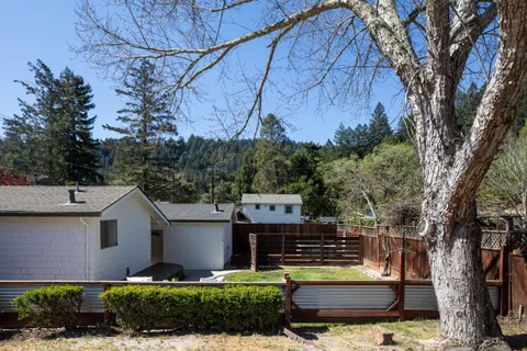 a view of a house with a yard and a large tree