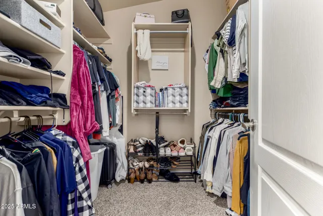 a view of walk in closet with clothes and shoes