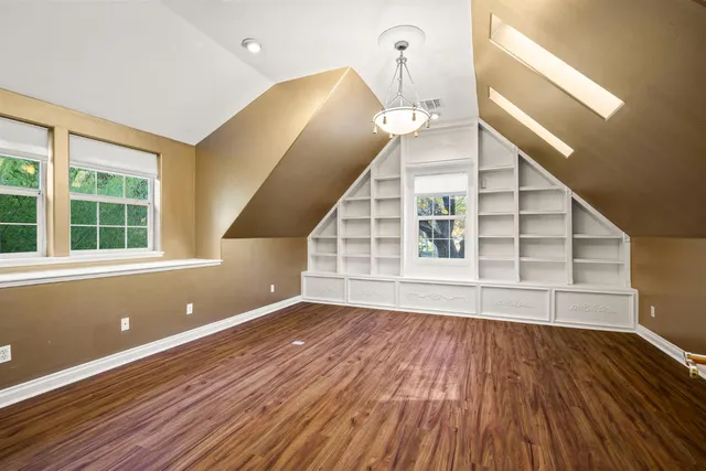 a view of an empty room with wooden floor and stairs