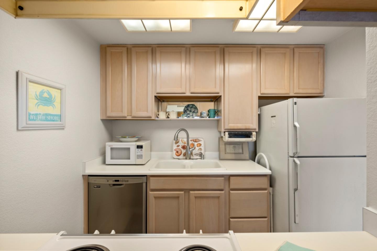 1 Surf Way, Unit 216 Monterey, CA 93940 - Photo 8 of 21 a kitchen with stainless steel appliances granite countertop a refrigerator sink stove and cabinets