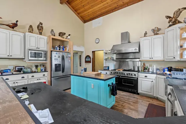 a kitchen with stainless steel appliances granite countertop a stove top oven a refrigerator a sink and dishwasher with white cabinets