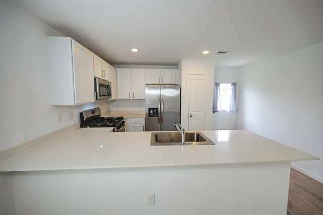 a kitchen with kitchen island a sink stainless steel appliances and white cabinets