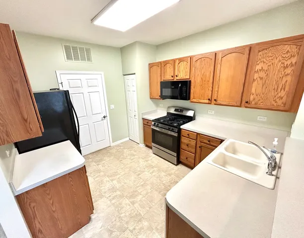 a kitchen with stainless steel appliances a stove a sink a microwave a refrigerator a counter top space and cabinets