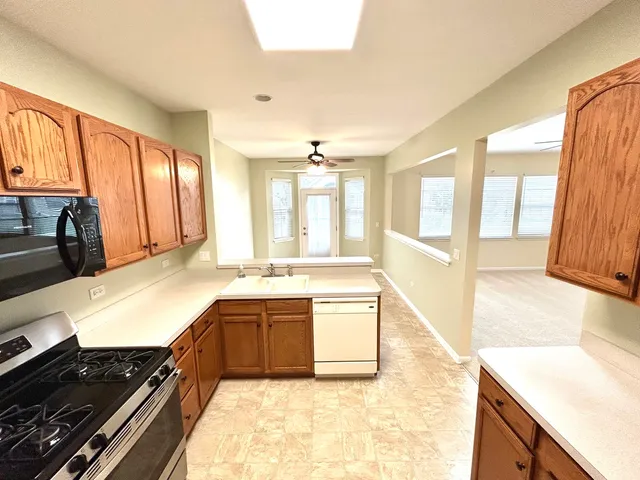 a large kitchen with kitchen island a large window a sink and stainless steel appliances