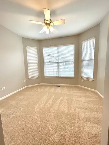 an empty room with windows and chandelier fan