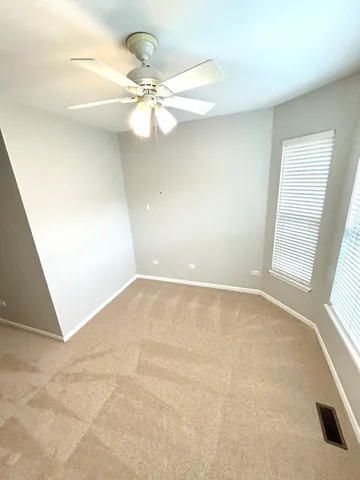 an empty room with windows and fan