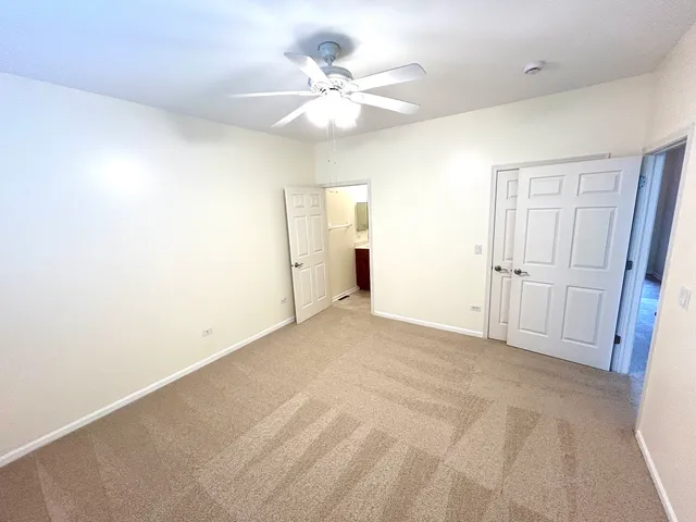 an empty room with chandelier fan and windows