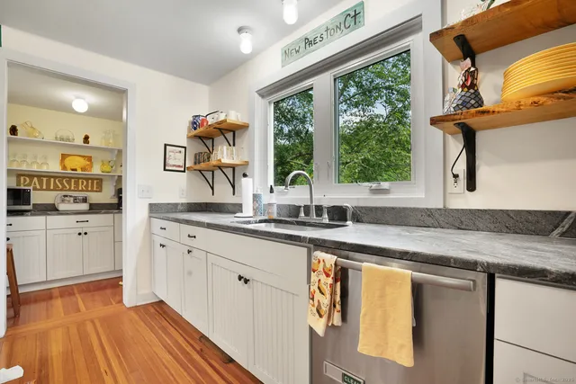 a kitchen with granite countertop a sink and white cabinets with wooden floor