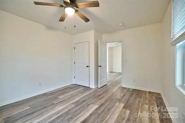 an empty room with wooden floor fan and windows