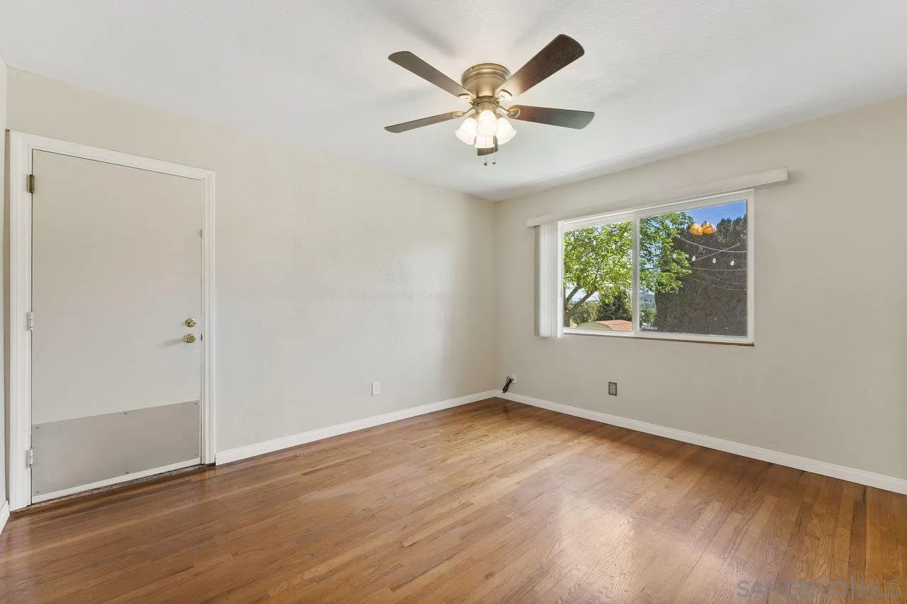 1822 Wight Way El Cajon, CA 92021 - Photo 19 of 45 an empty room with wooden floor chandelier fan and windows