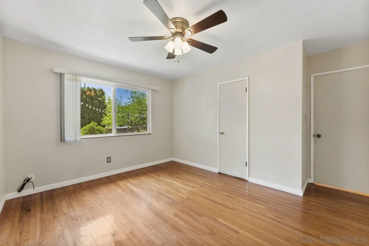 1822 Wight Way El Cajon, CA 92021 - Photo 20 of 45 an empty room with wooden floor chandelier fan and windows
