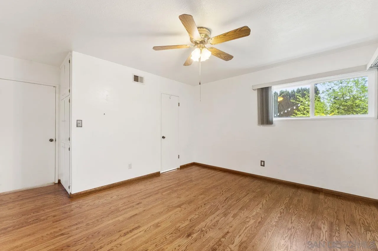 1822 Wight Way El Cajon, CA 92021 - Photo 24 of 45 an empty room with wooden floor fan and windows